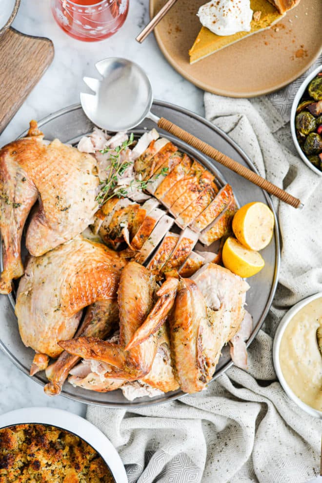 top view of a carved whole turkey sitting in the center of a thanksgiving spread