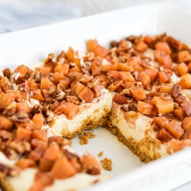 side view of a dish of apple pie cheesecake bars with one bar missing