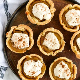 the top view of a plate of mini pumpkin pies topped with homemade whipped cream