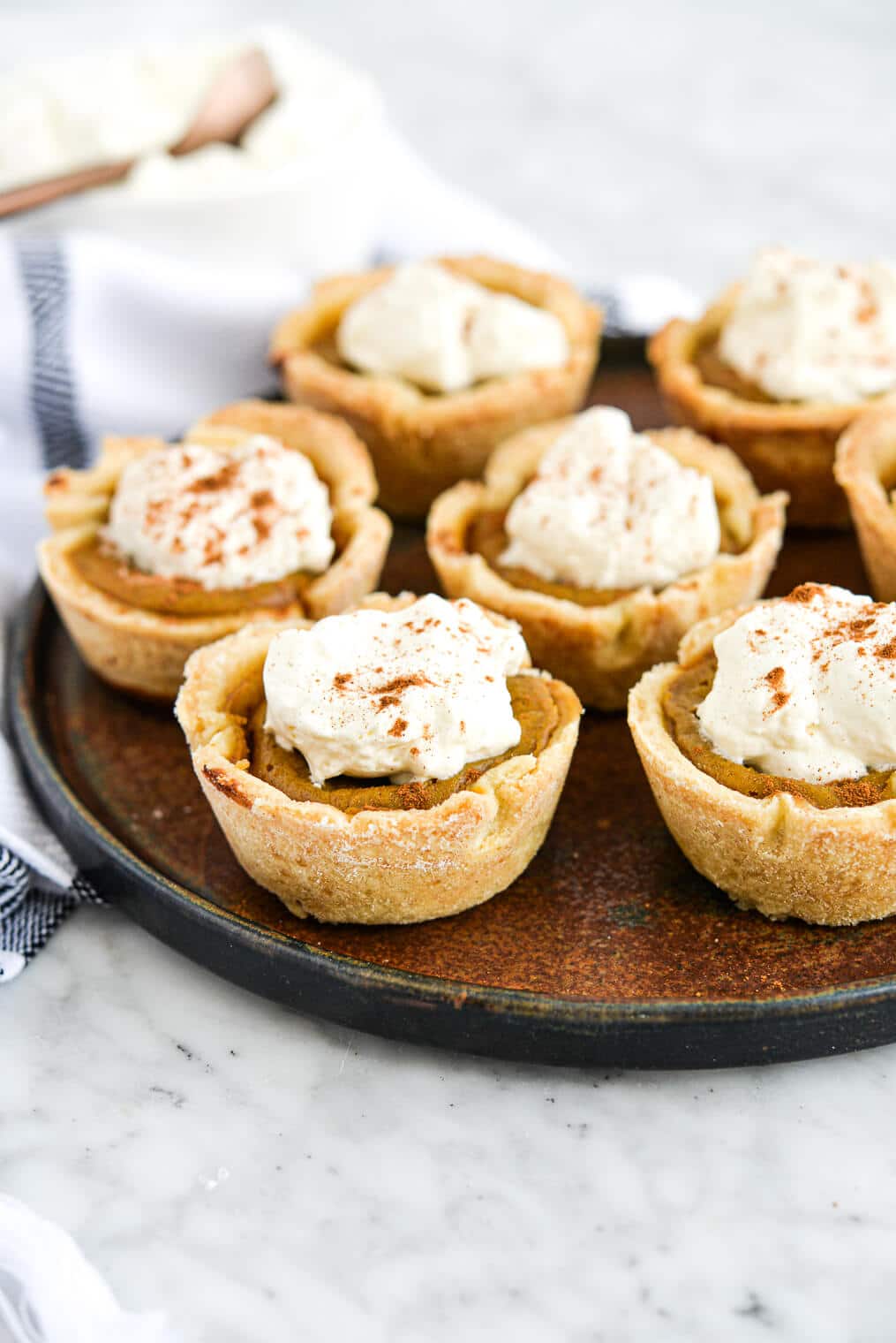 the side view of a plate of mini pumpkin pies topped with homemade whipped cream