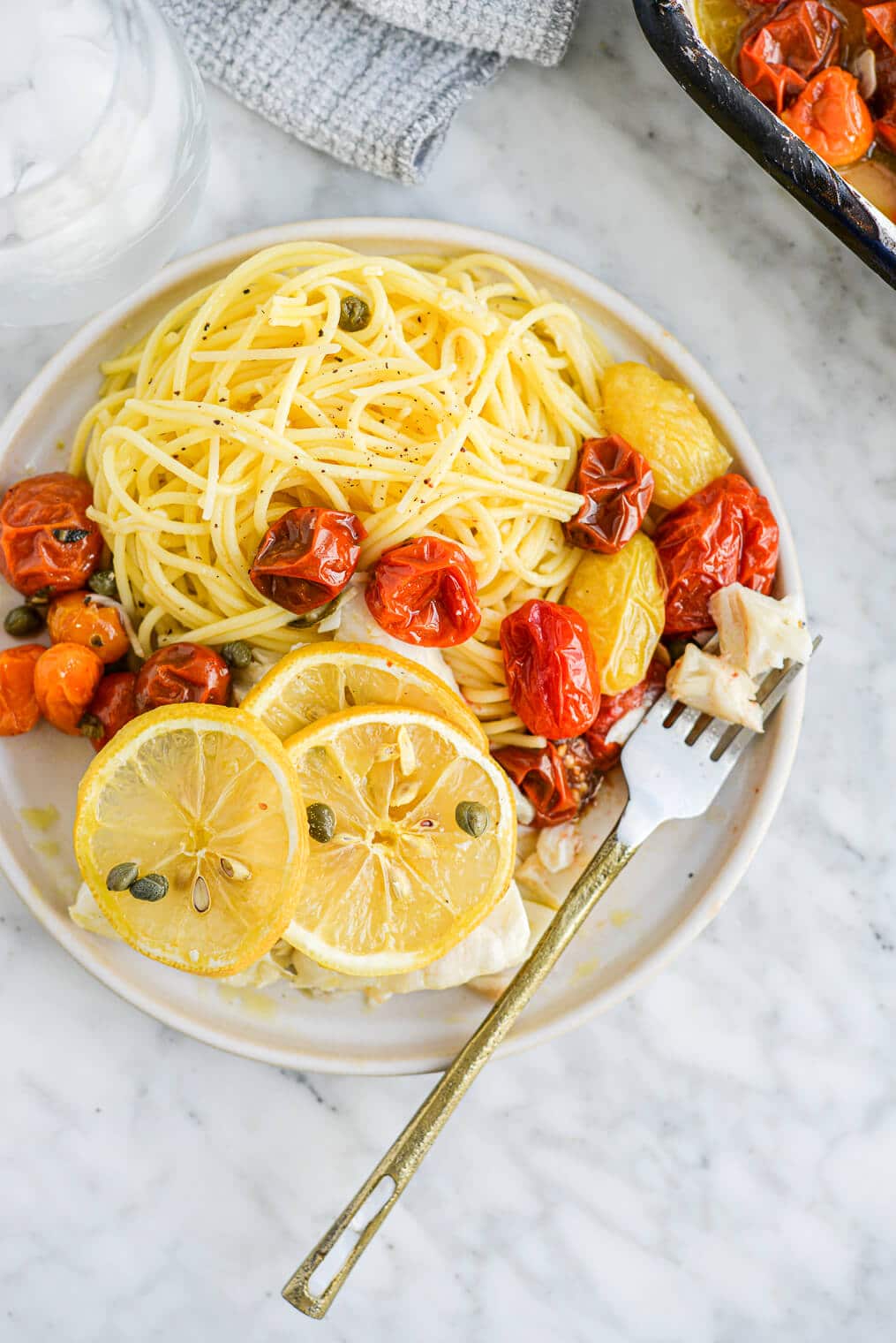 the top view of a plate of lemon garlic baked cod, roasted tomatoes, and garlic parmesan pasta