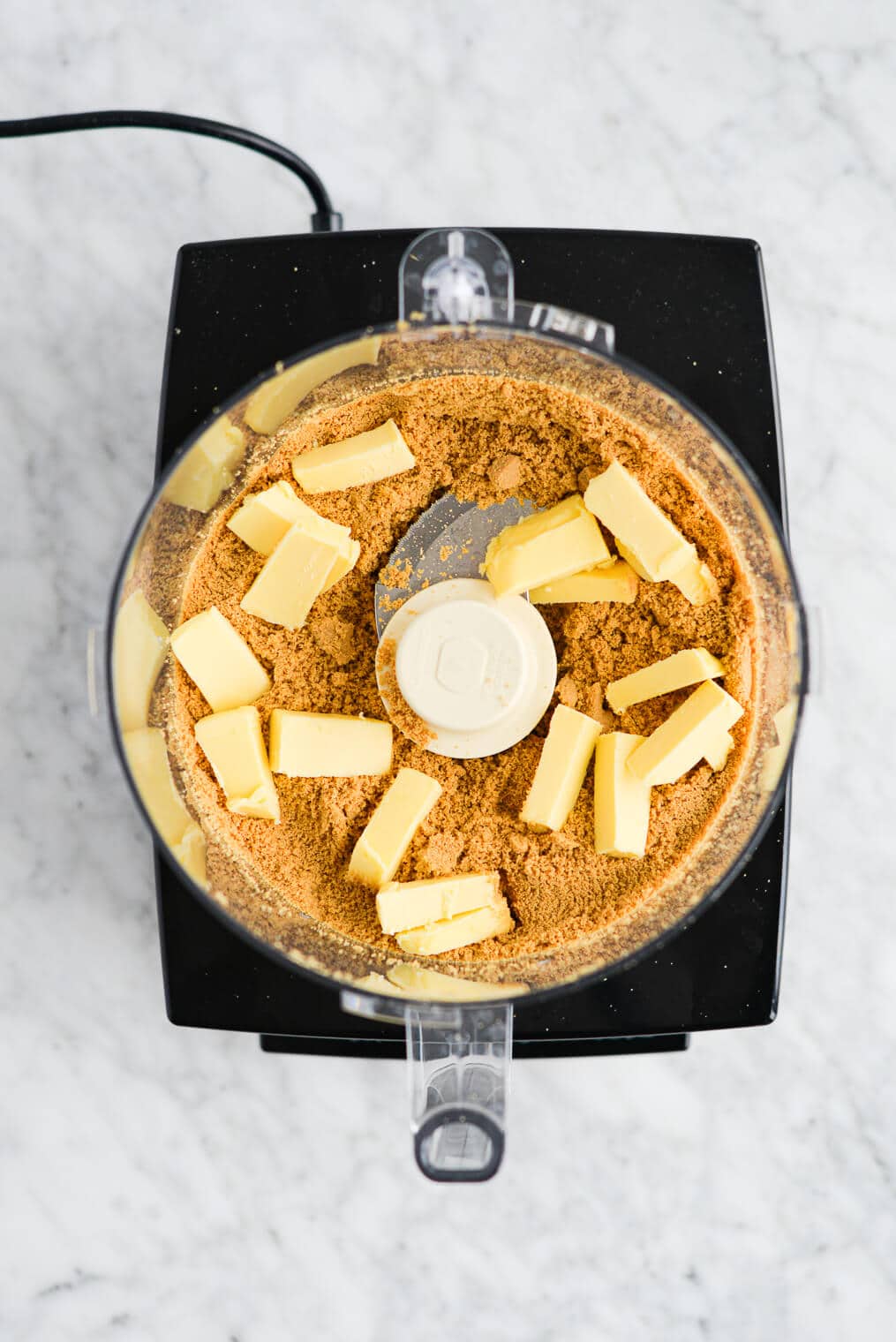 finely processed graham cracker crumbs in a food processor with solid butter pieces