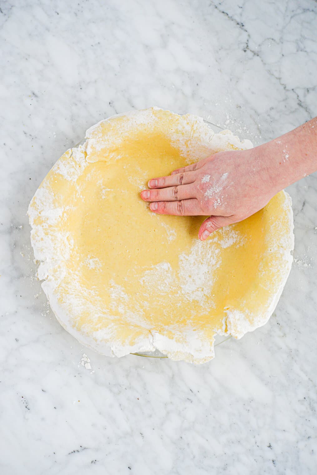 a rolled out pie crust being pressed into a pie pan