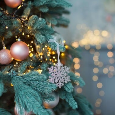 christmas tree with rose gold ornaments against a twinkle light background