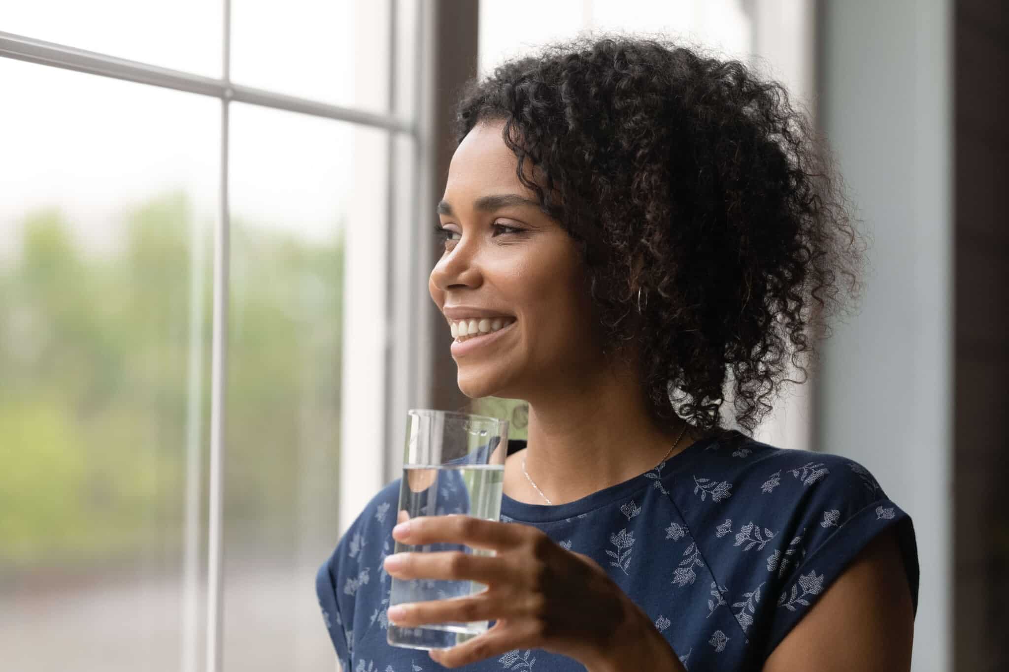 woman drinking water and looking out the window