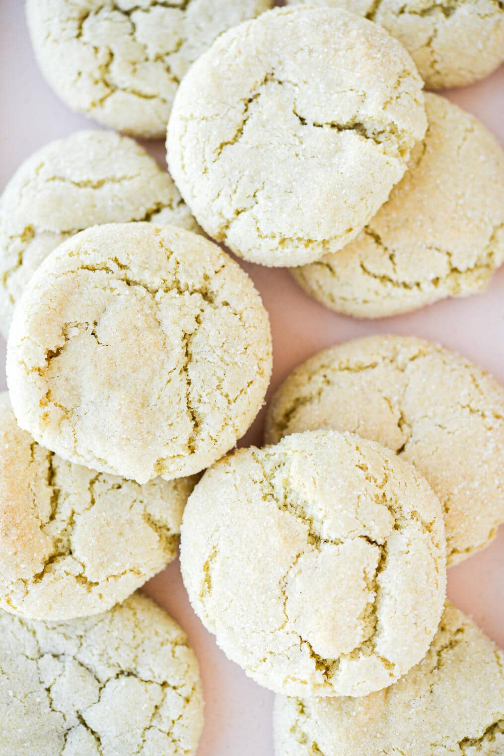 a close up of chewy cream cheese sugar cookies laying on a light pink plate