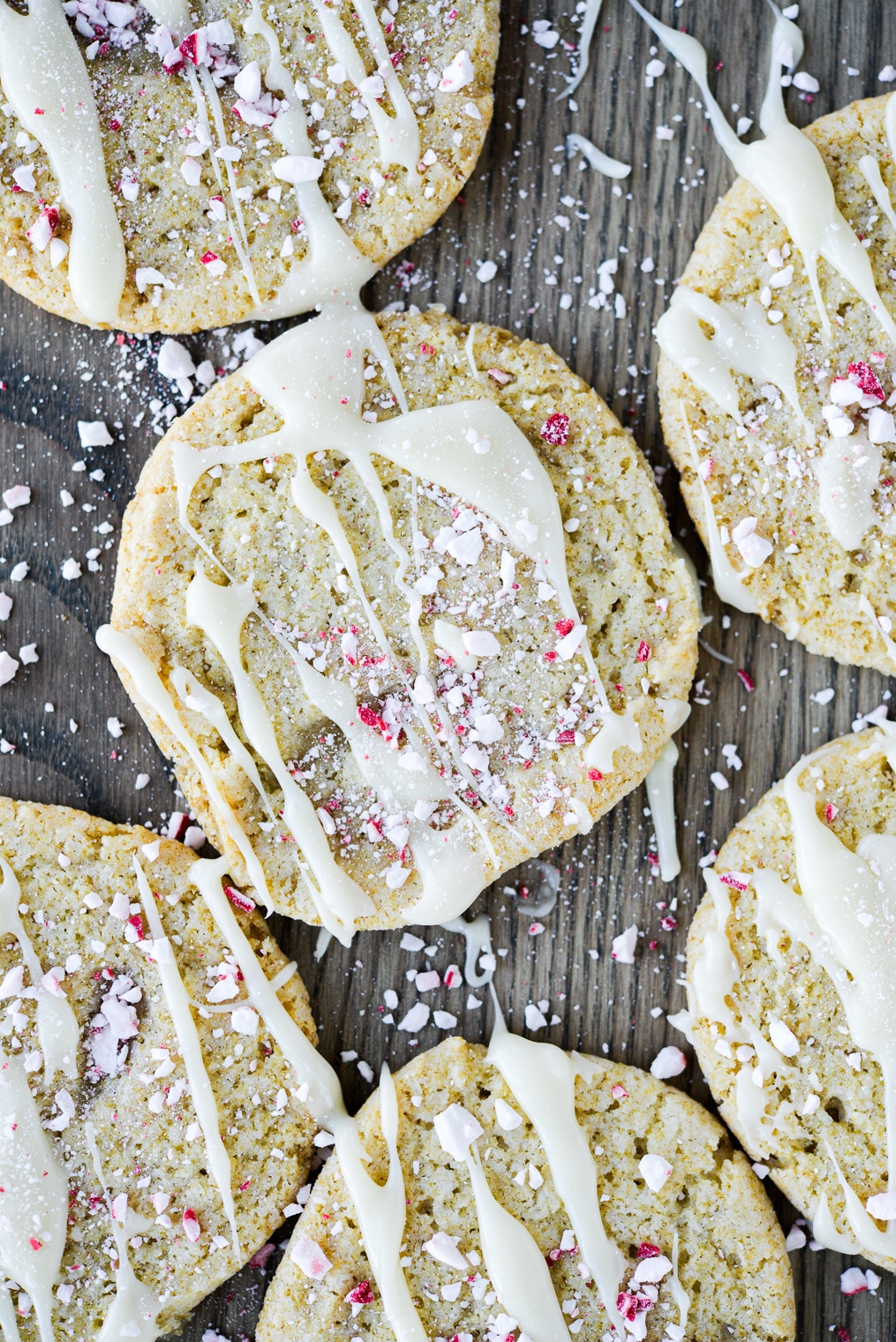 sugar cookies drizzled with white chocolate and crushed peppermints on a wooden surface