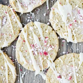 white chocolate peppermint cookies drizzled with white chocolate and crushed peppermint on a wooden surface