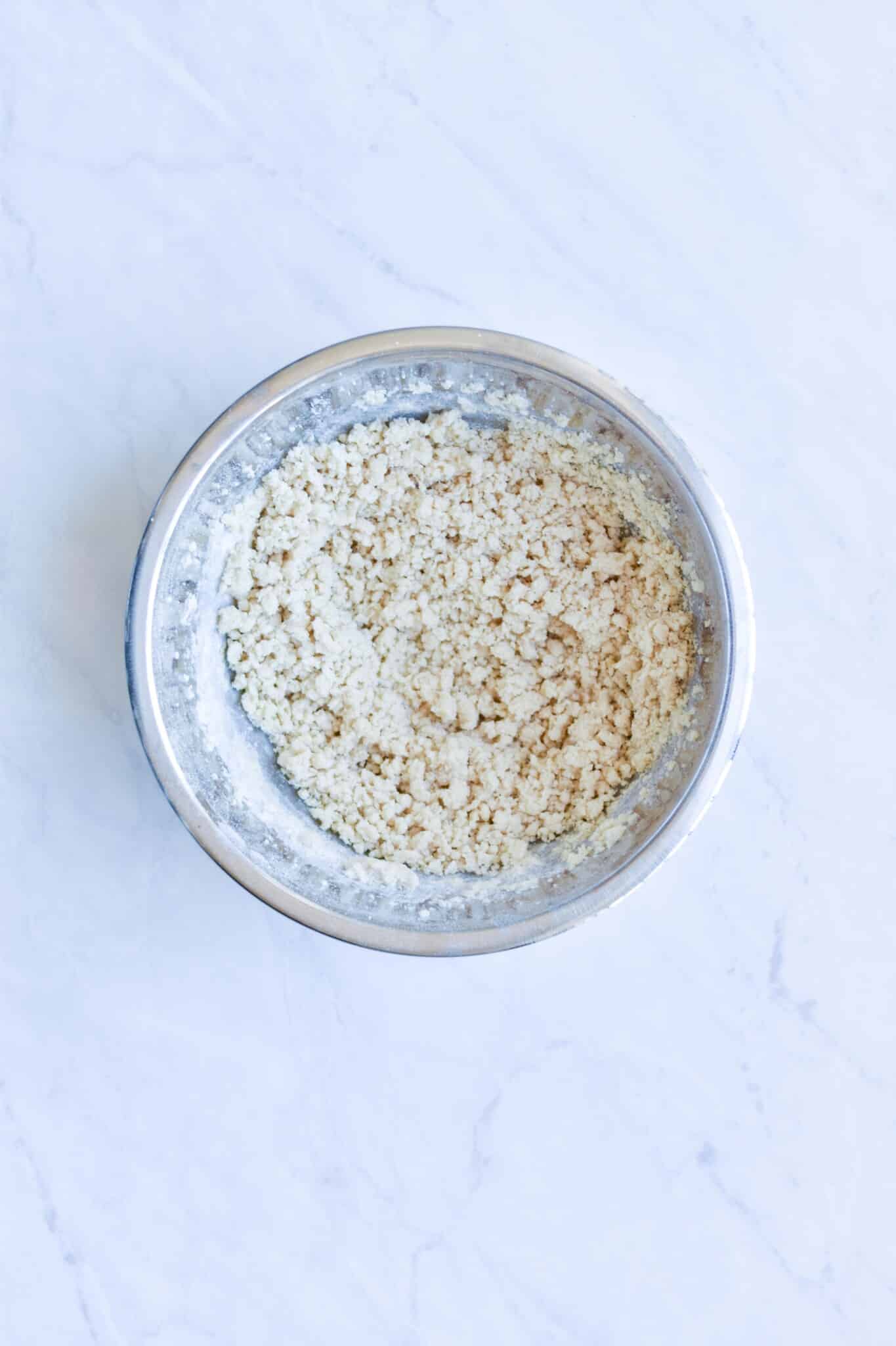 metal bowl filled with crumbly cookie dough on a marble surface