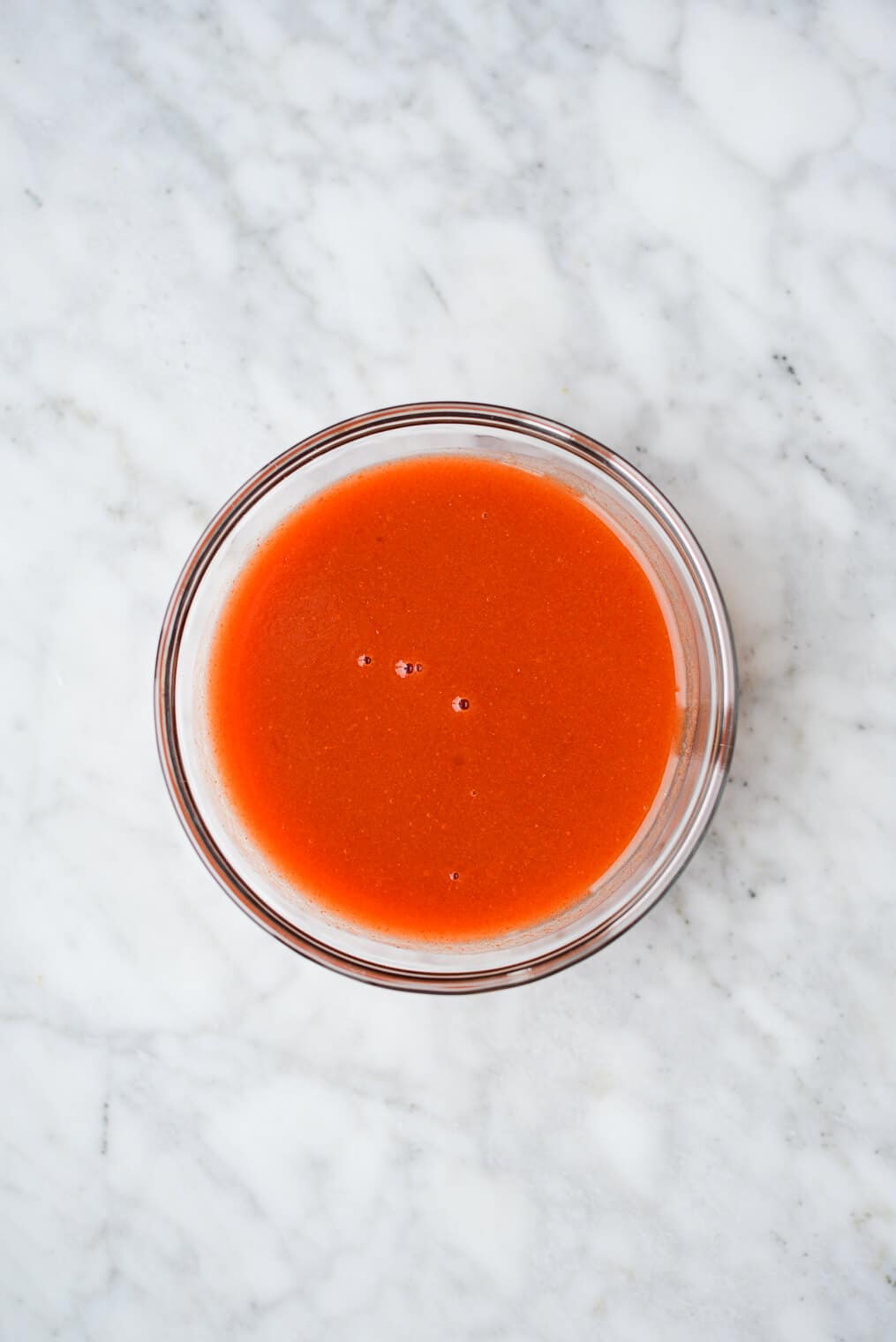 a small bowl of buffalo sauce sitting on a marble surface