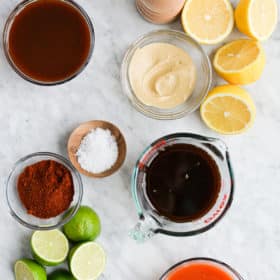 the ingredients for 5 different chicken marinades (lemon dijon, teriyaki, buffalo, BBQ, and taco) sitting on a marble surface