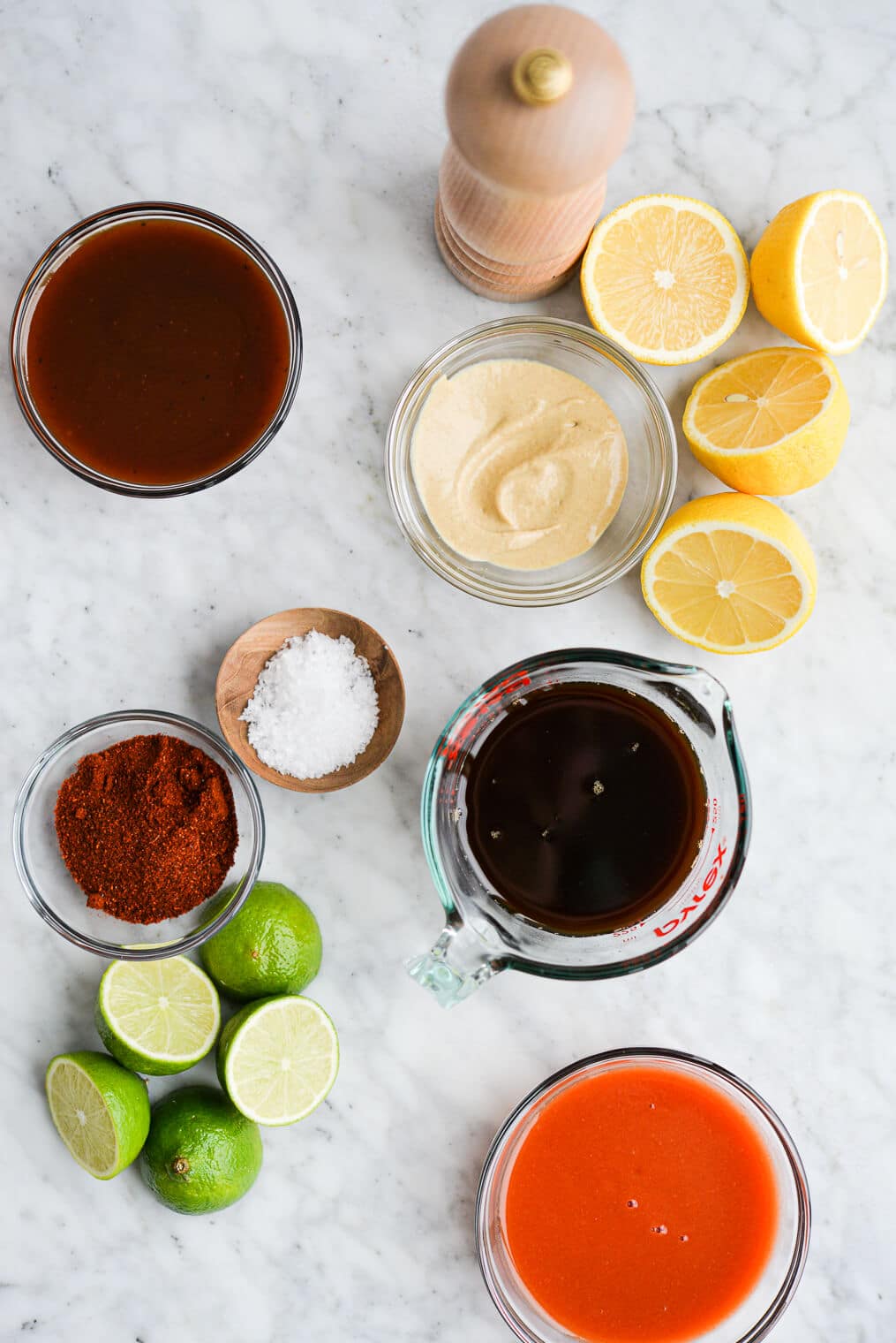 the ingredients for 5 different chicken marinades (lemon dijon, teriyaki, buffalo, BBQ, and taco) sitting on a marble surface