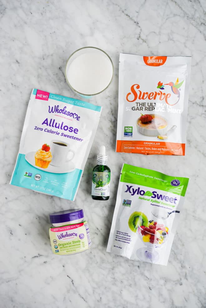 6 sugar substitutes (allulose, swerve, xylitol, stevia, and monk fruit) laying on a marble surface