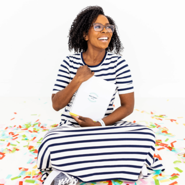Shunta Grant of The Best Today Brand holding the Best Today Guide while sitting on a confetti covered floor