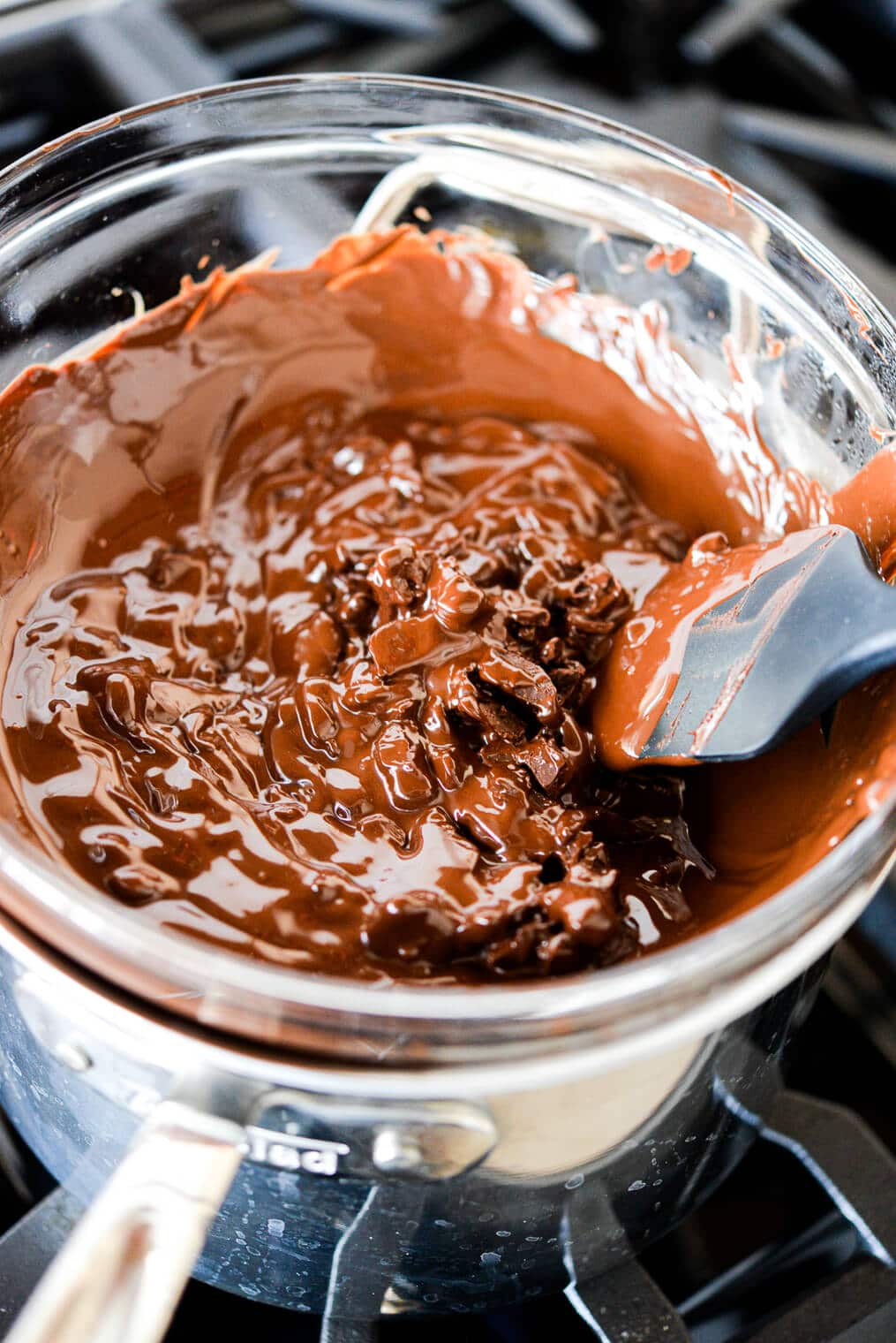 dark chocolate melting in a glass bowl over a pot of hot water on the stovetop