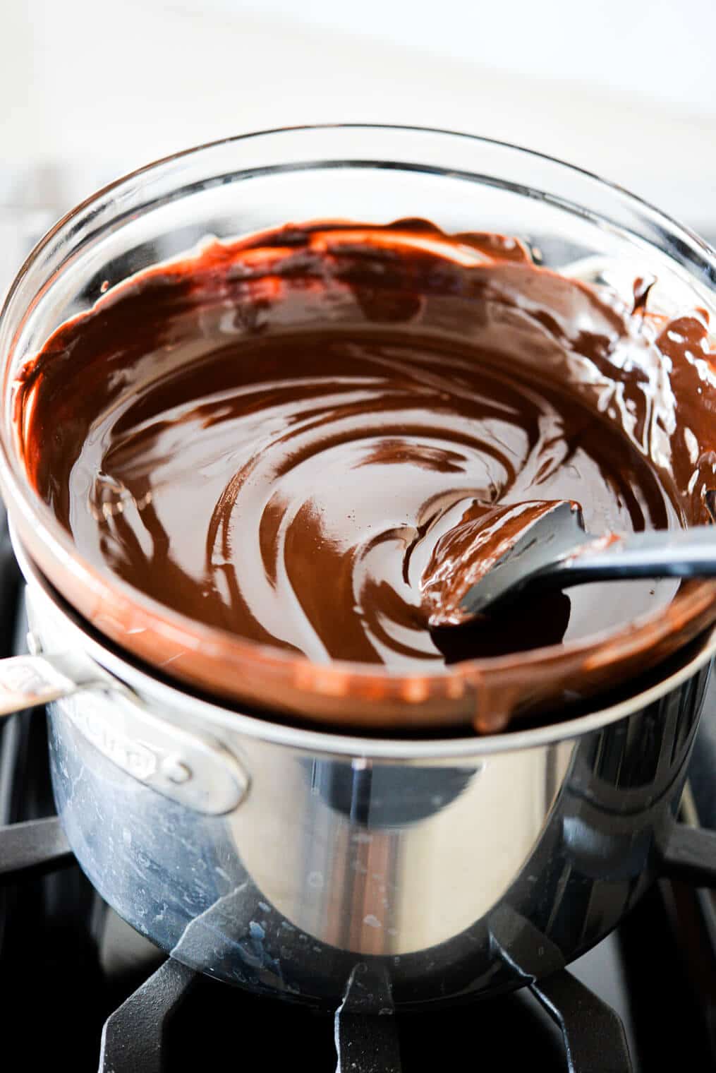 chocolate melting in a glass bowl over a pot of water on the stovetop