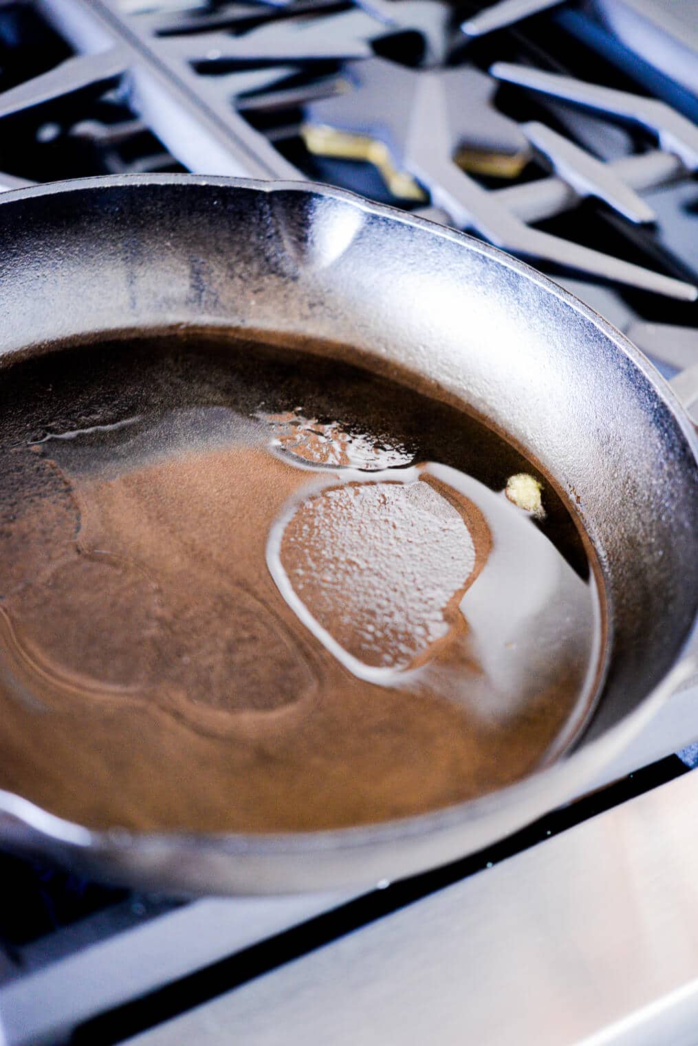 melted ghee sitting in a cast iron pan on the stovetop