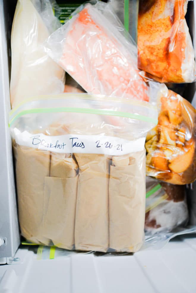 a large ziplock bag labeled "breakfast tacos 2-26-21" sitting in the freezer in front of various other frozen foods