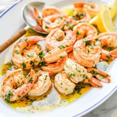 a oblong white dish filled with shrimp scampi sitting on a marble surface