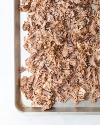 a sheet pan of seasoned shredded pork before going into the oven to make carnitas