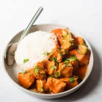 a plate of tikka masala and a bed of rice with a spoon resting on the plate