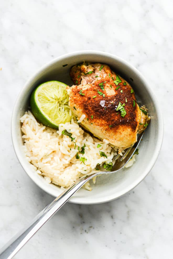 a serving of chicken and rice bake in a small bowl with a lime wedge squeezed over it