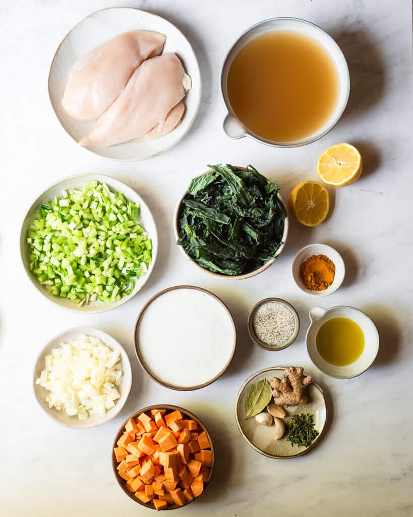 all of the ingredients of healing turmeric chicken soup sitting on a marble surface