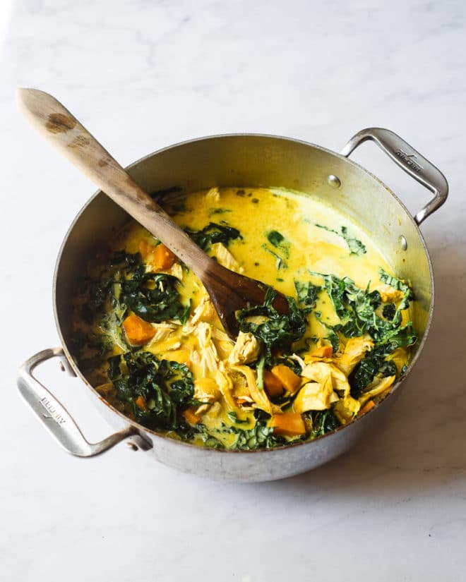 a large pot of healing turmeric chicken soup with a wooden spoon sticking out of it