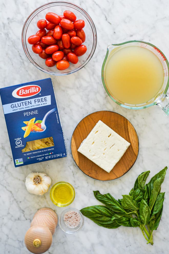 ingredients for baked feta pasta sitting on a marble surface
