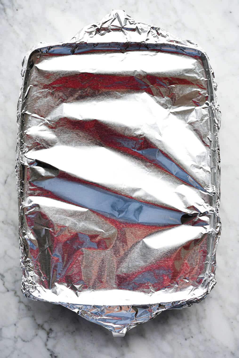 a baking dish covered tightly with foil sitting on a marble surface