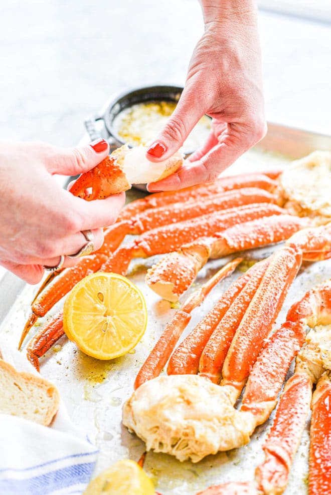 een vrouw trekt het vlees van de krab been over een krab bakken bakplaat