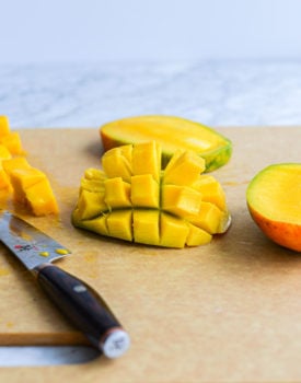 a halved mango with the flesh cut into cubes and the flesh of the mango turned inside out