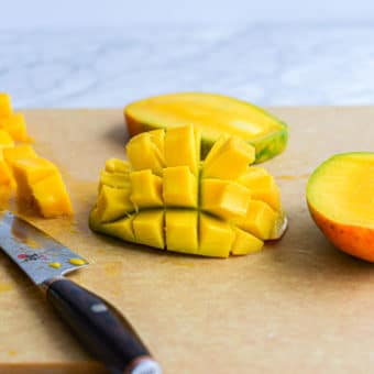 a halved mango with the flesh cut into cubes and the flesh of the mango turned inside out