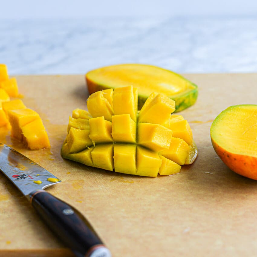 a halved mango with the flesh cut into cubes and the flesh of the mango turned inside out