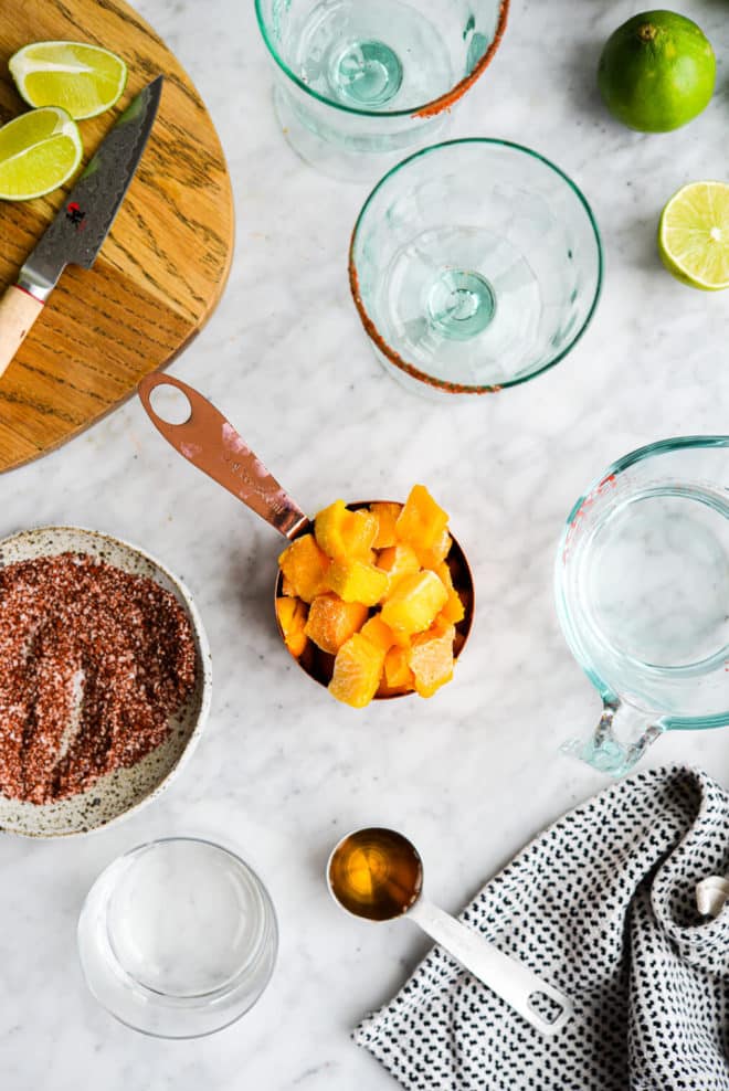 the ingredients for mango margaritas sitting on a marble surface