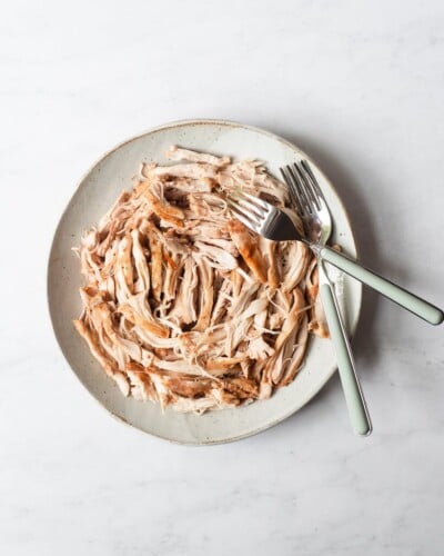 a plate of shredded chicken with two forks next to it