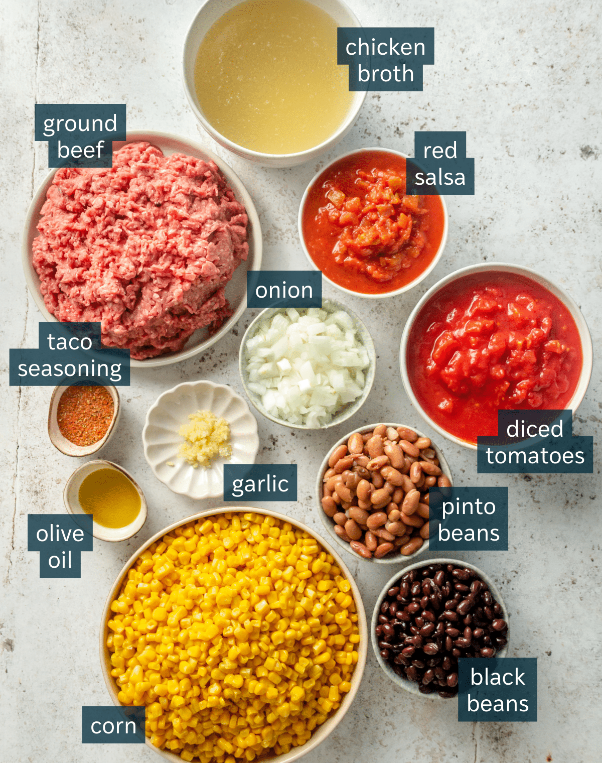 All of the ingredients that are needed for taco soup on a light gray surface.