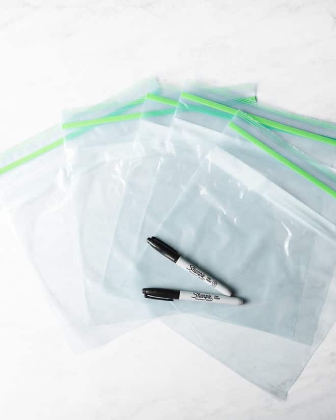 5 gallon size ziplock bags with two sharpies laying on top of them on a white marble surface