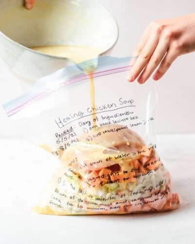 freezer meal healing chicken soup in a labeled ziplock bag on a marble surface