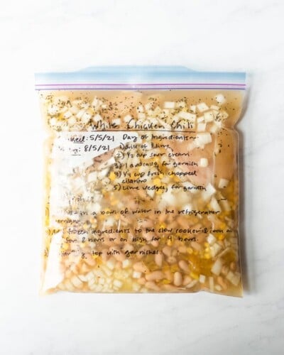 freezer meal white chicken chili in a labeled ziplock bag on a marble surface