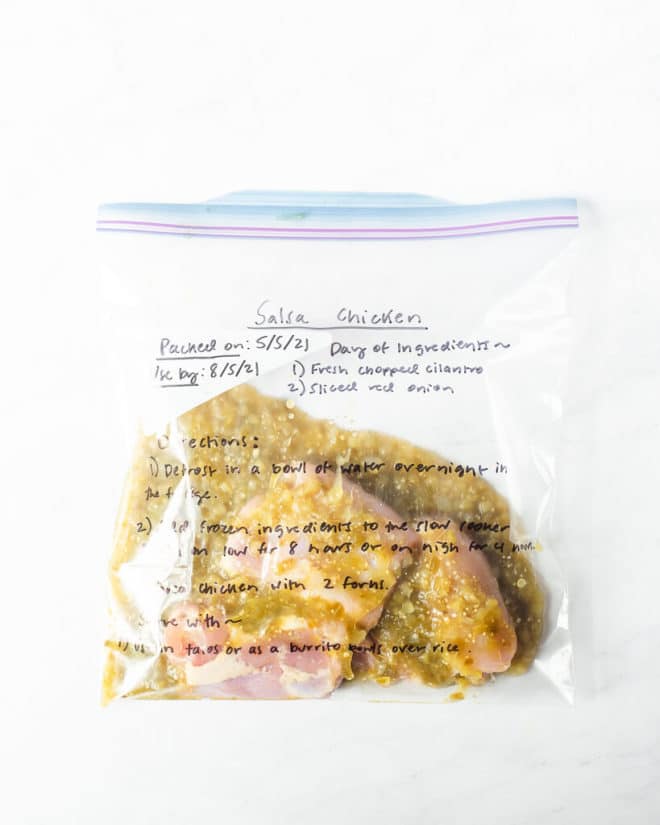 freezer meal salsa chicken in a labeled ziplock bag on a marble surface