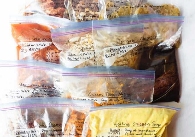 10 freezer meals in gallon size labeled ziplock bags laying on a white surface
