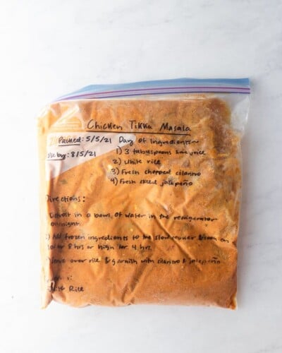 freezer meal chicken tikka masala in a labeled ziplock bag on a marble surface