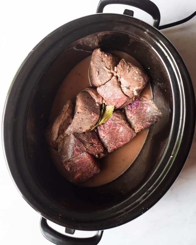 a raw, thawed freezer meal in a slow cooker sitting on a marble surface