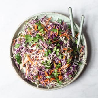 a plate filled with creamy Mexican coleslaw sitting on a marble surface