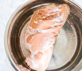 a big chunk of frozen chicken breast in the stainless steel pot of an instant pot