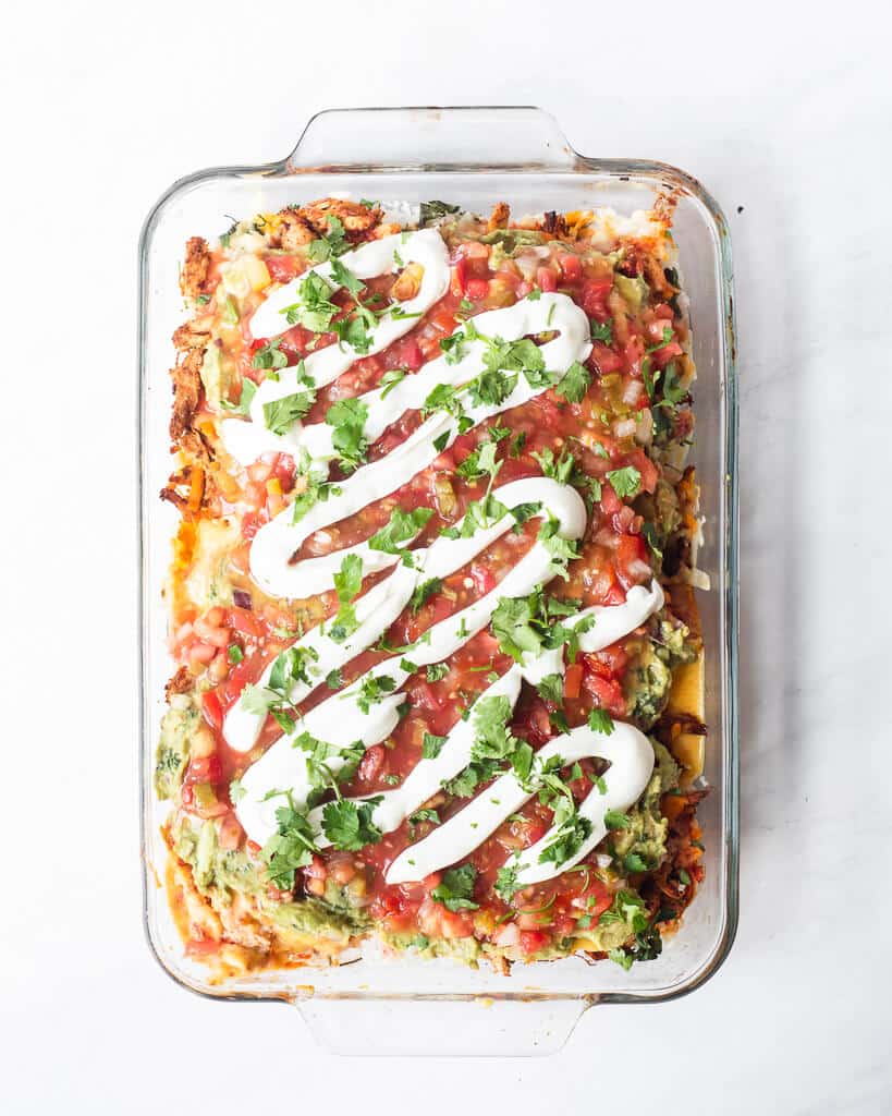 a full serving dish of chicken taco casserole with a garnish of sour cream and cilantro on top