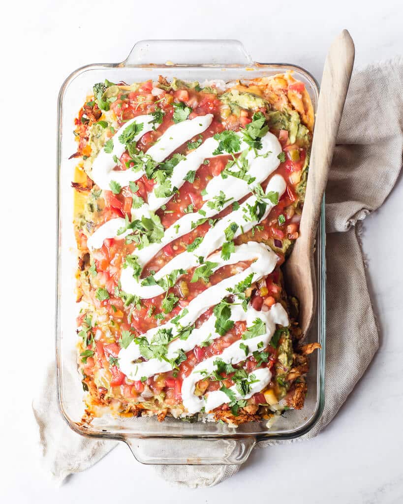 a full serving dish of chicken taco casserole with a garnish of sour cream and cilantro on top