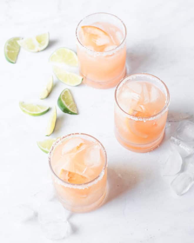 a salt rimmed glass of palomas sitting on a marble surface