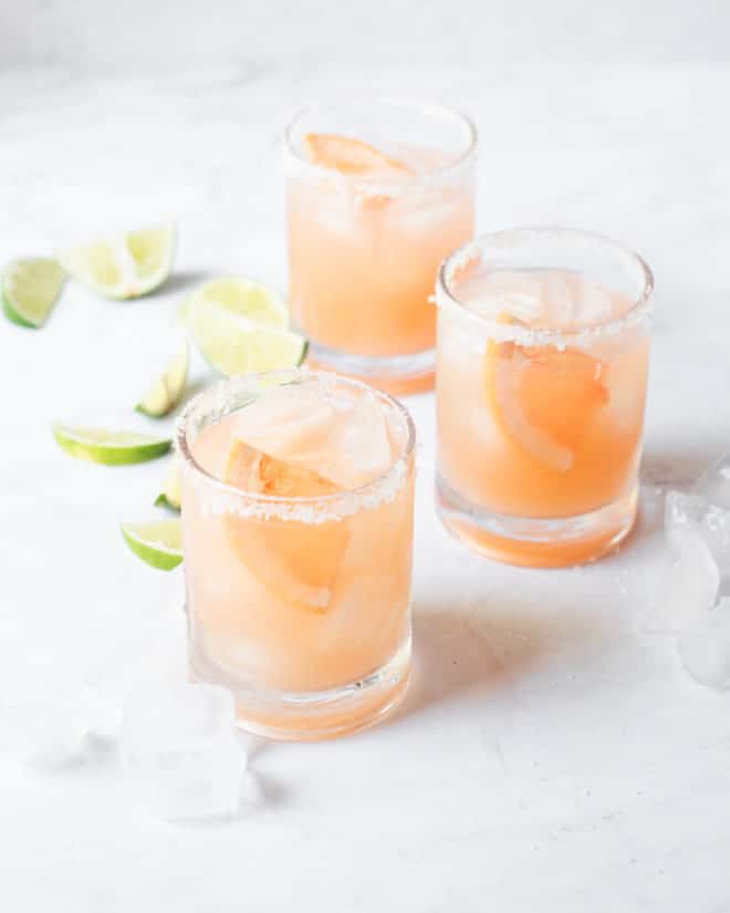 a salt rimmed glass of palomas sitting on a marble surface